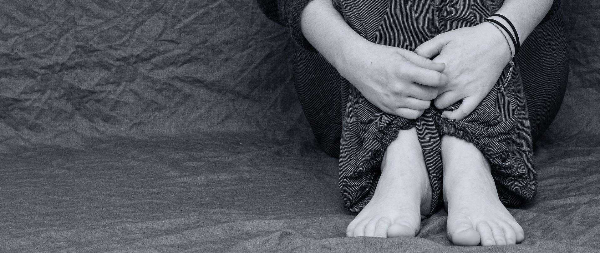 Person sitting on the floor, hugging her knees